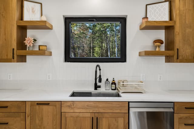The Salem House kitchen sink beneath a picture window overlooking the wooded property.