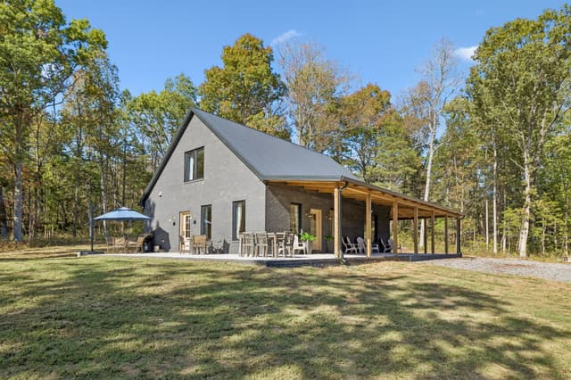 The Salem House exterior and long wraparound porch surrounded by trees.